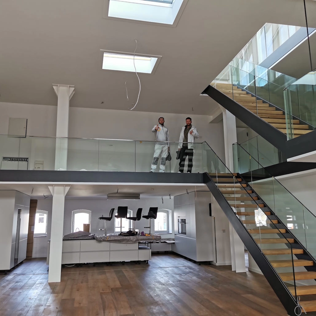 Modernes Loft mit Galerie, Glasgeländer und Holztreppe, saniert von KraftBau, steht für exklusive Innenausbauten und hochwertige Raumgestaltung.