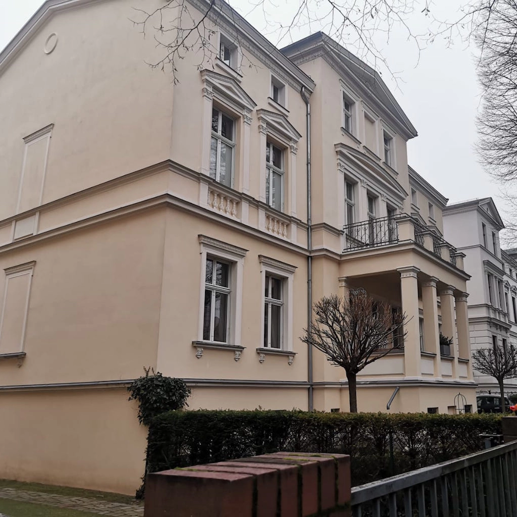 Elegante Stadtvilla mit klassischer Stuckfassade und Säulen, fachgerecht renoviert von KraftBau für Werterhalt und stilvolle Außenwirkung.